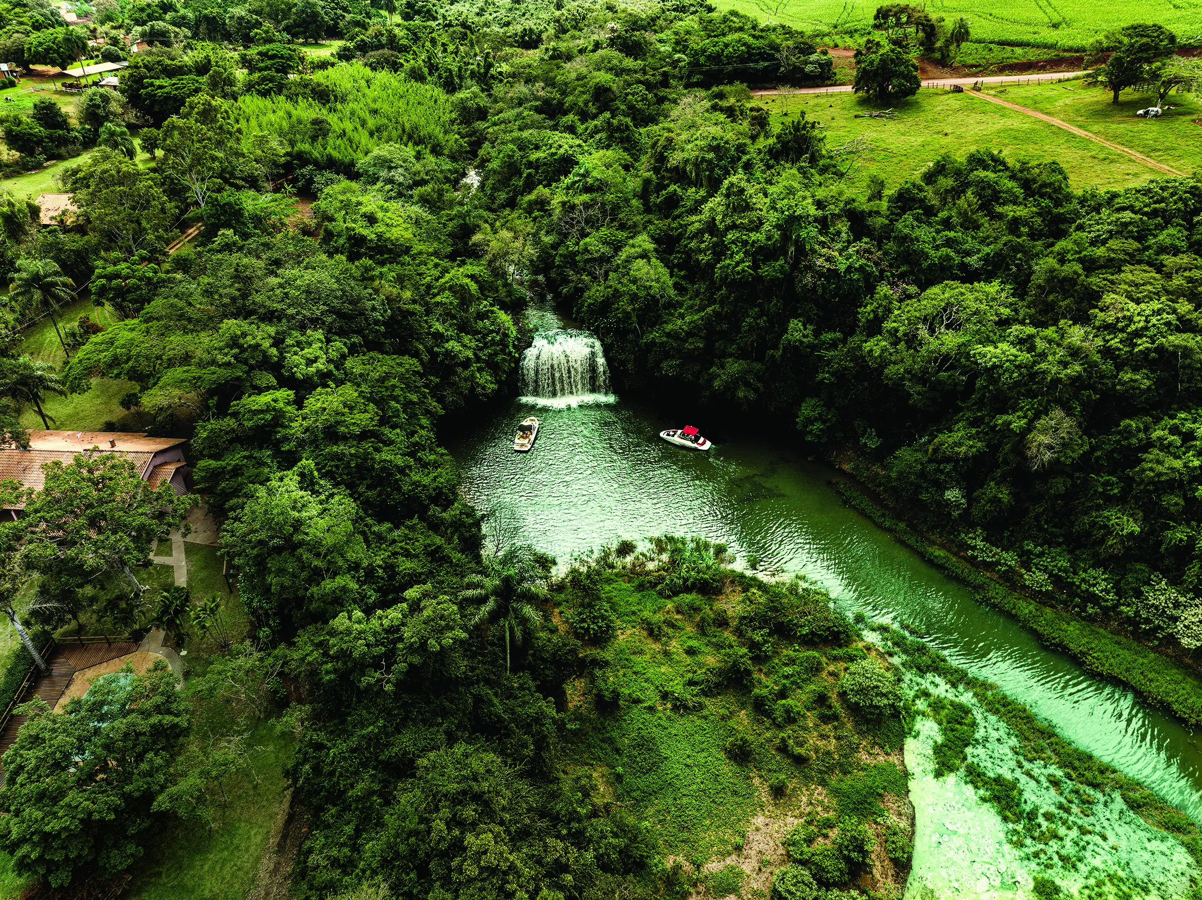 Lancha parada em frente a uma cachoeira na represa, no meio da mata