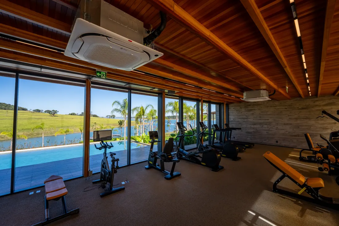 Academia com parede de vidro de frente para a piscina