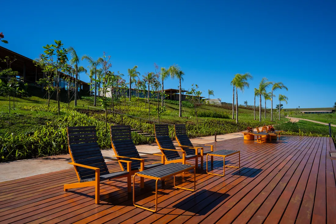 Deck de madeira com espreguiçadeiras à beira da represa