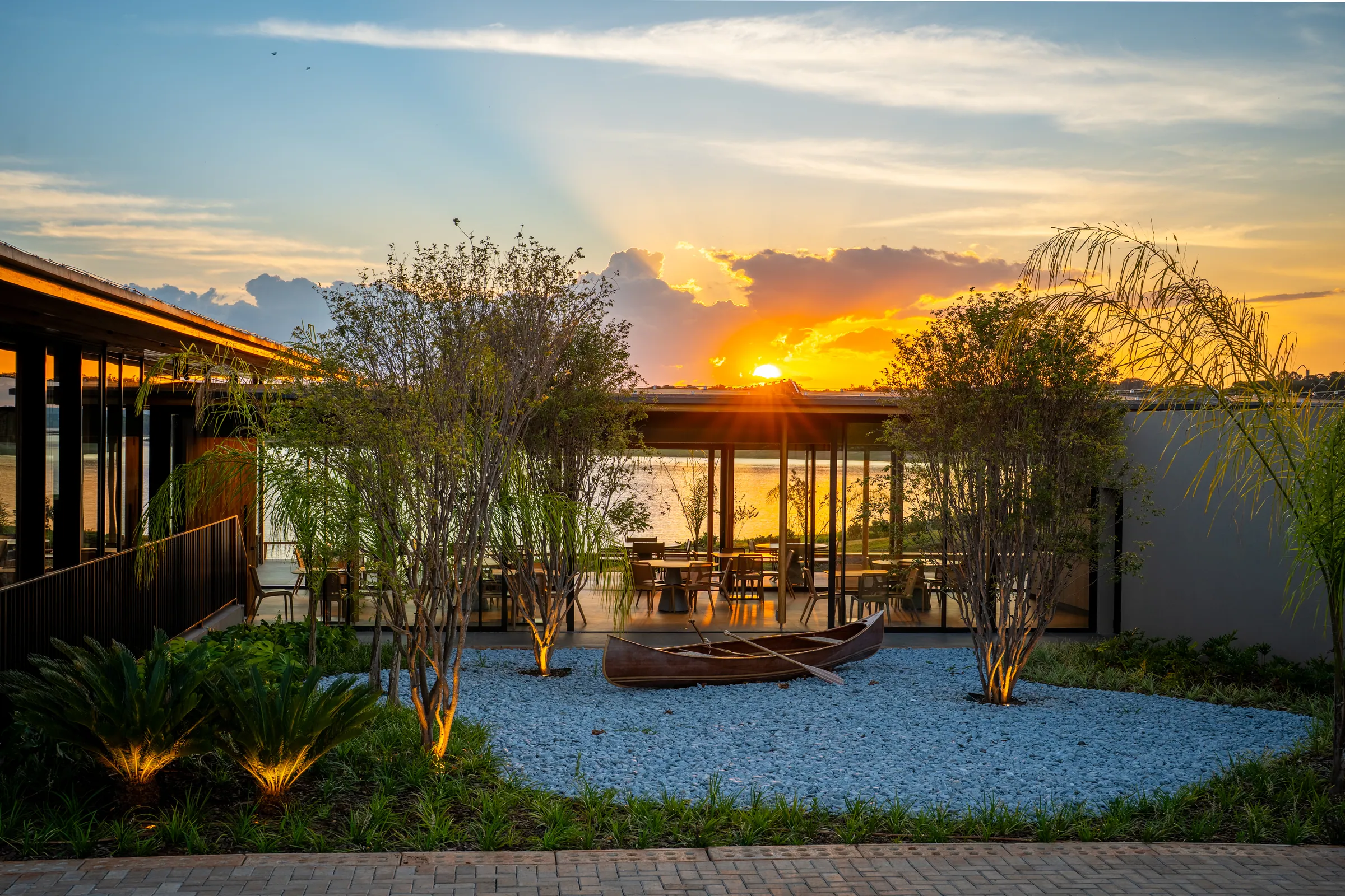 Pátio do restaurante com o pôr do sol sobre a represa ao fundo